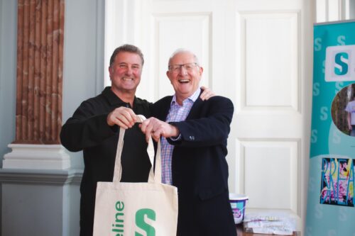 Two men holding a tote bag with a Safeline logo on.