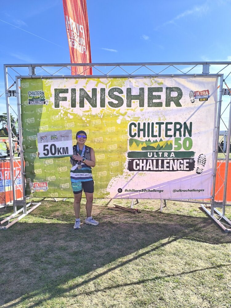 Fundraiser holding a banner that says 50km after completing the Chiltern 50 Ultra Challenge