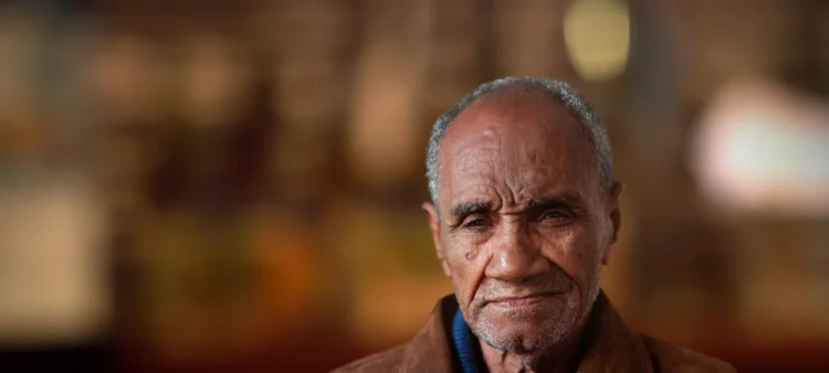 Very old man with grizzled hair. Tanned skin and brown eyes