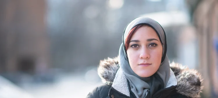 Lady with a headscarf. Wearing a parka. Pale skin with large soft brown eyes