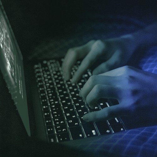 Hands typing in the dark on a keyboard