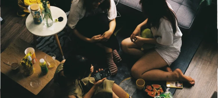 Friends gathered on the floor talking to each other.